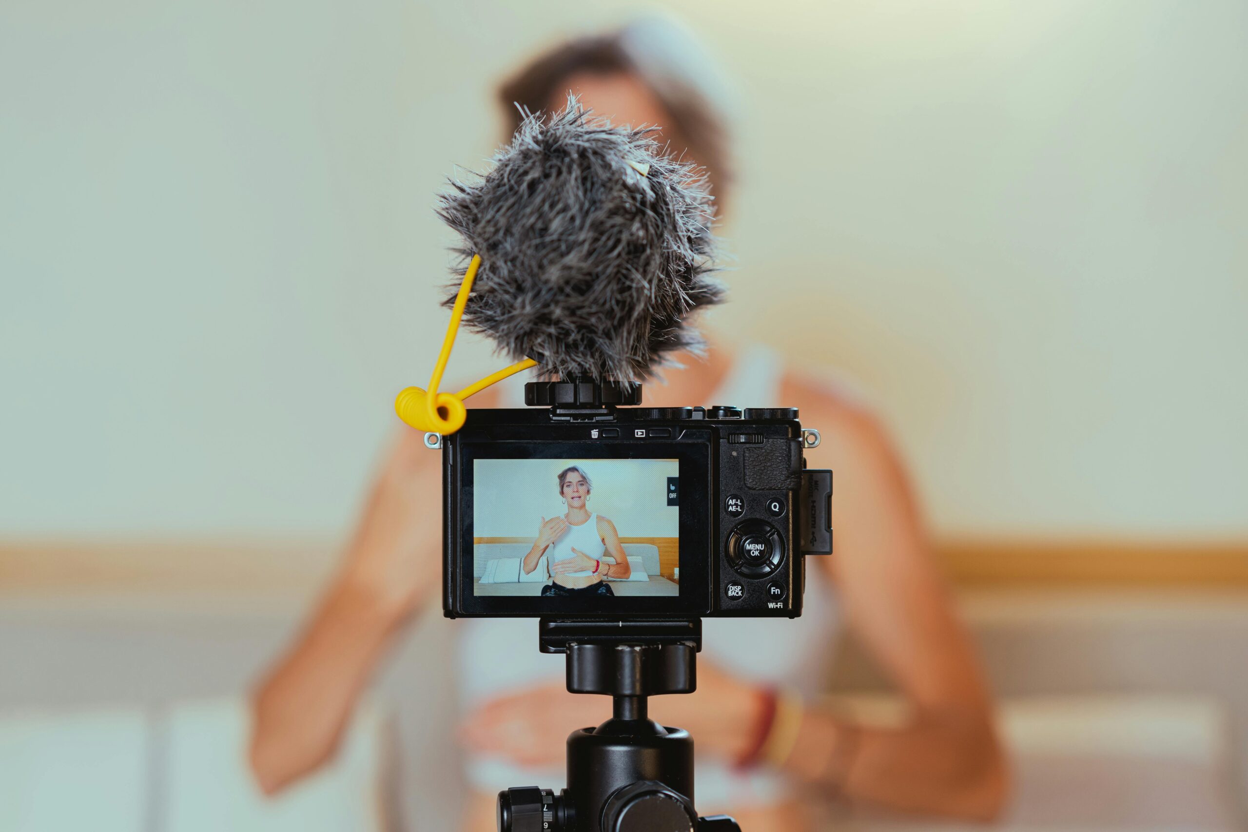 Elderly woman engages in vlogging using camera and microphone, embracing modern technology.